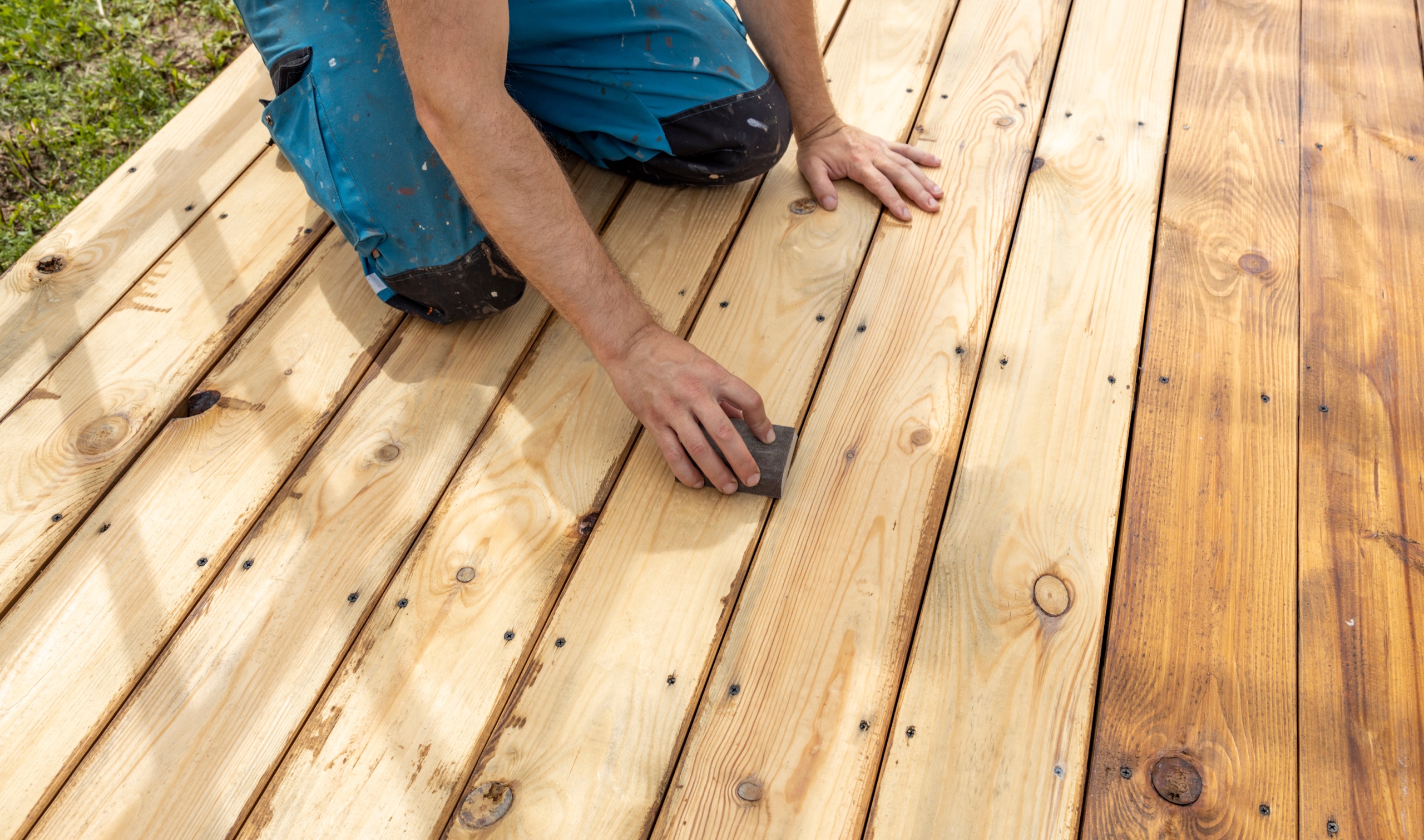 Craftsperson sanding newly installed wood deck boards