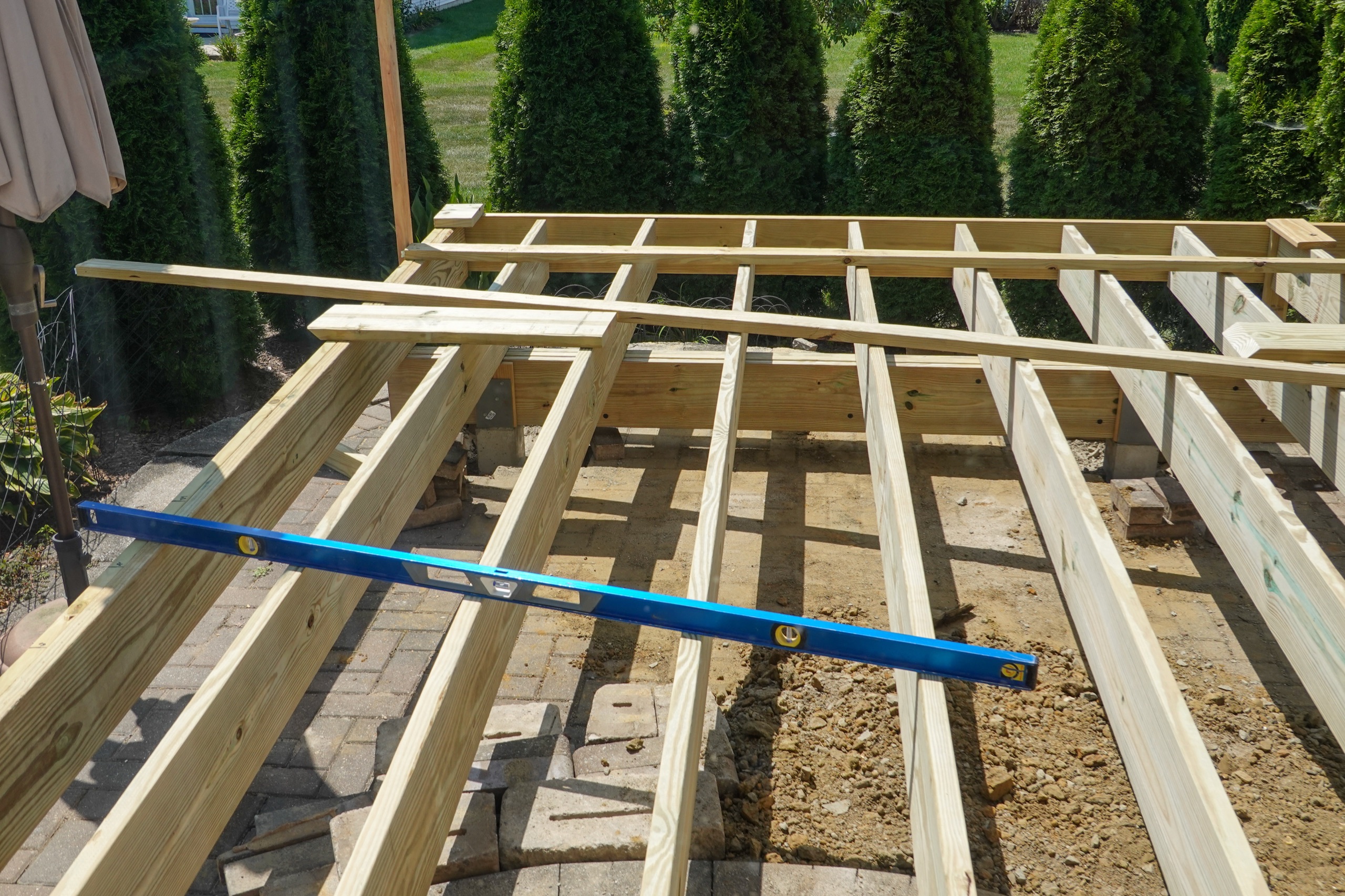 Wood deck framing under construction with a level across the joists