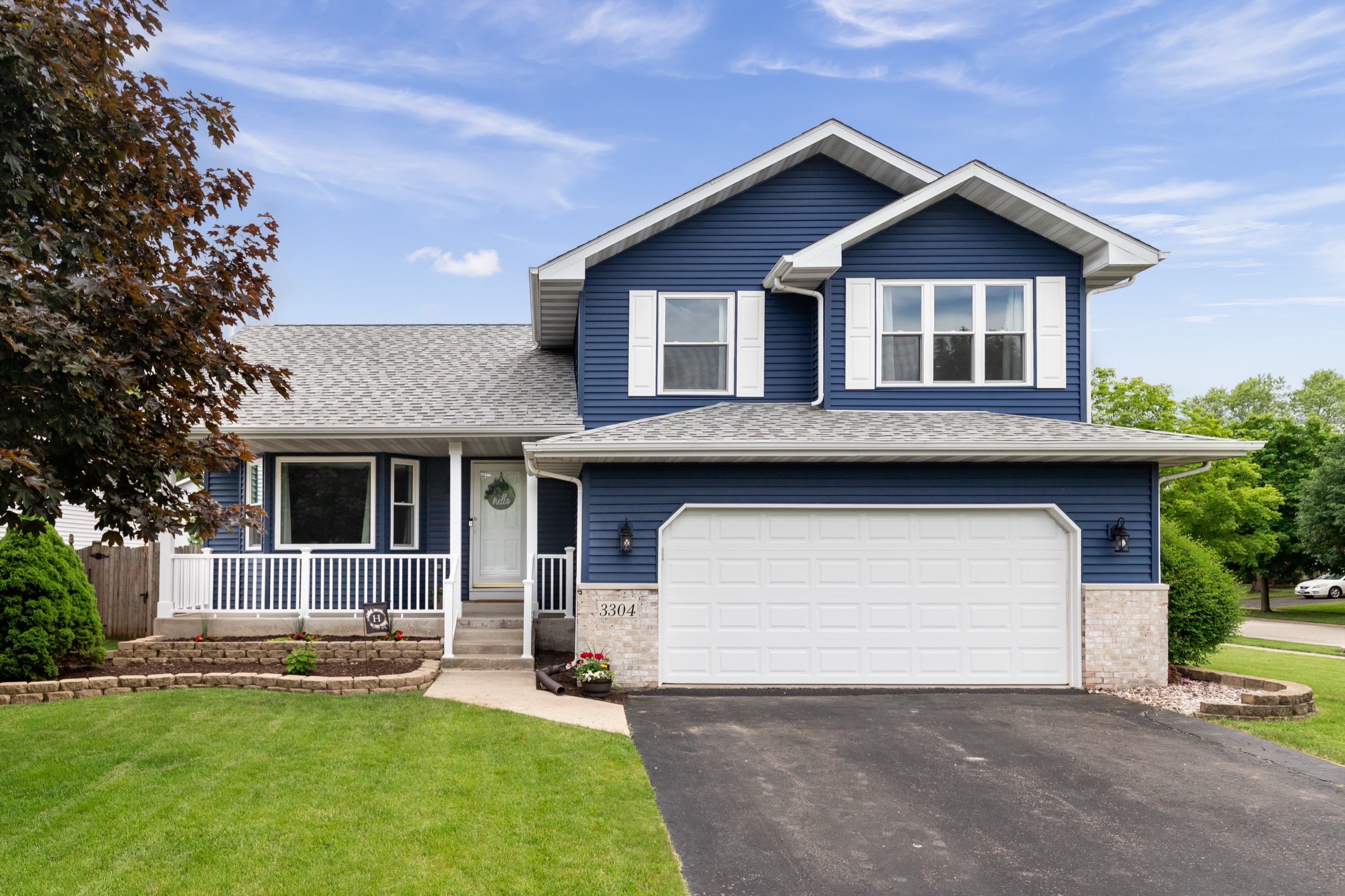 Finished home with blue siding, new windows, a porch, and a paved driveway
