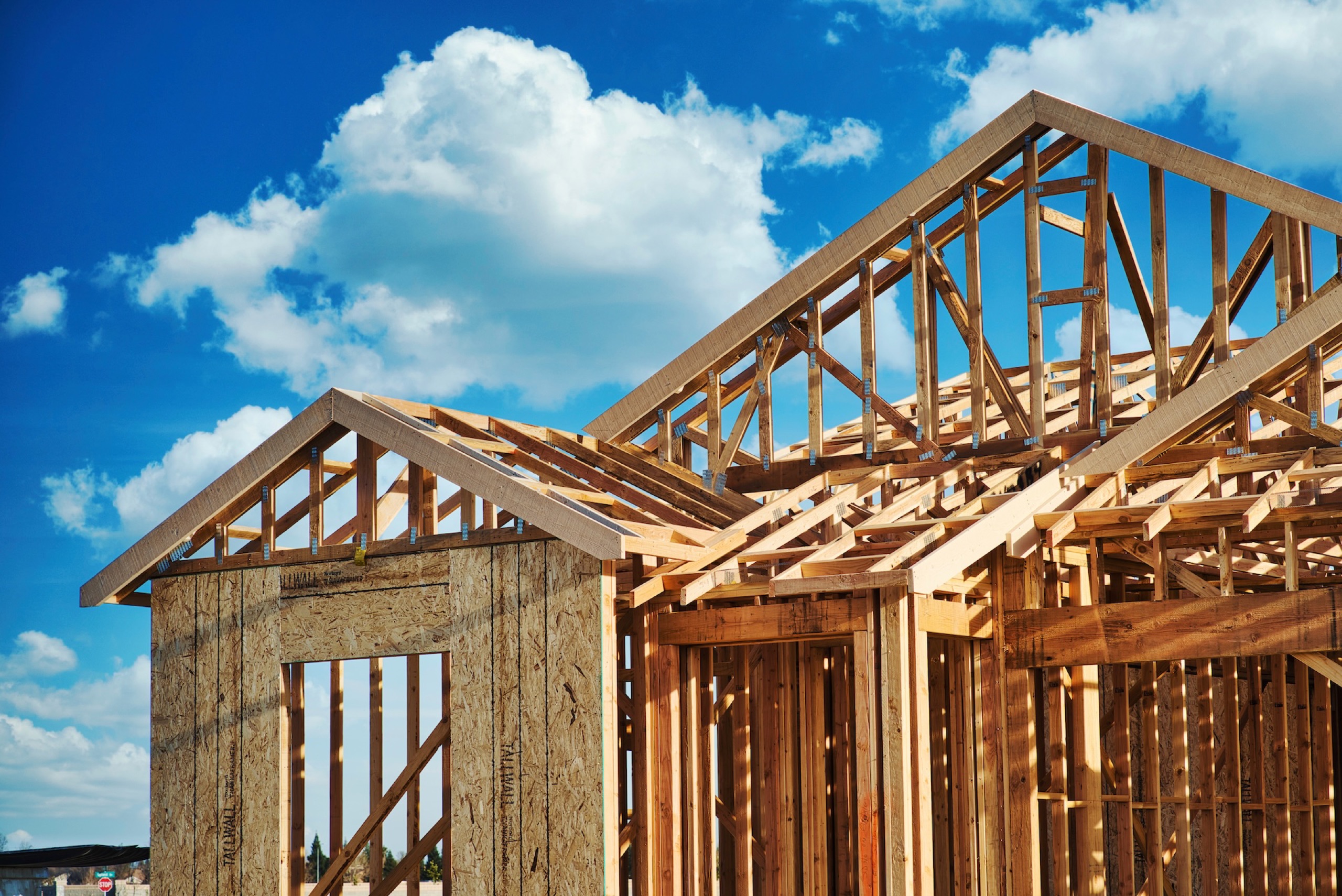 Wood framing on a residential construction project under a blue sky