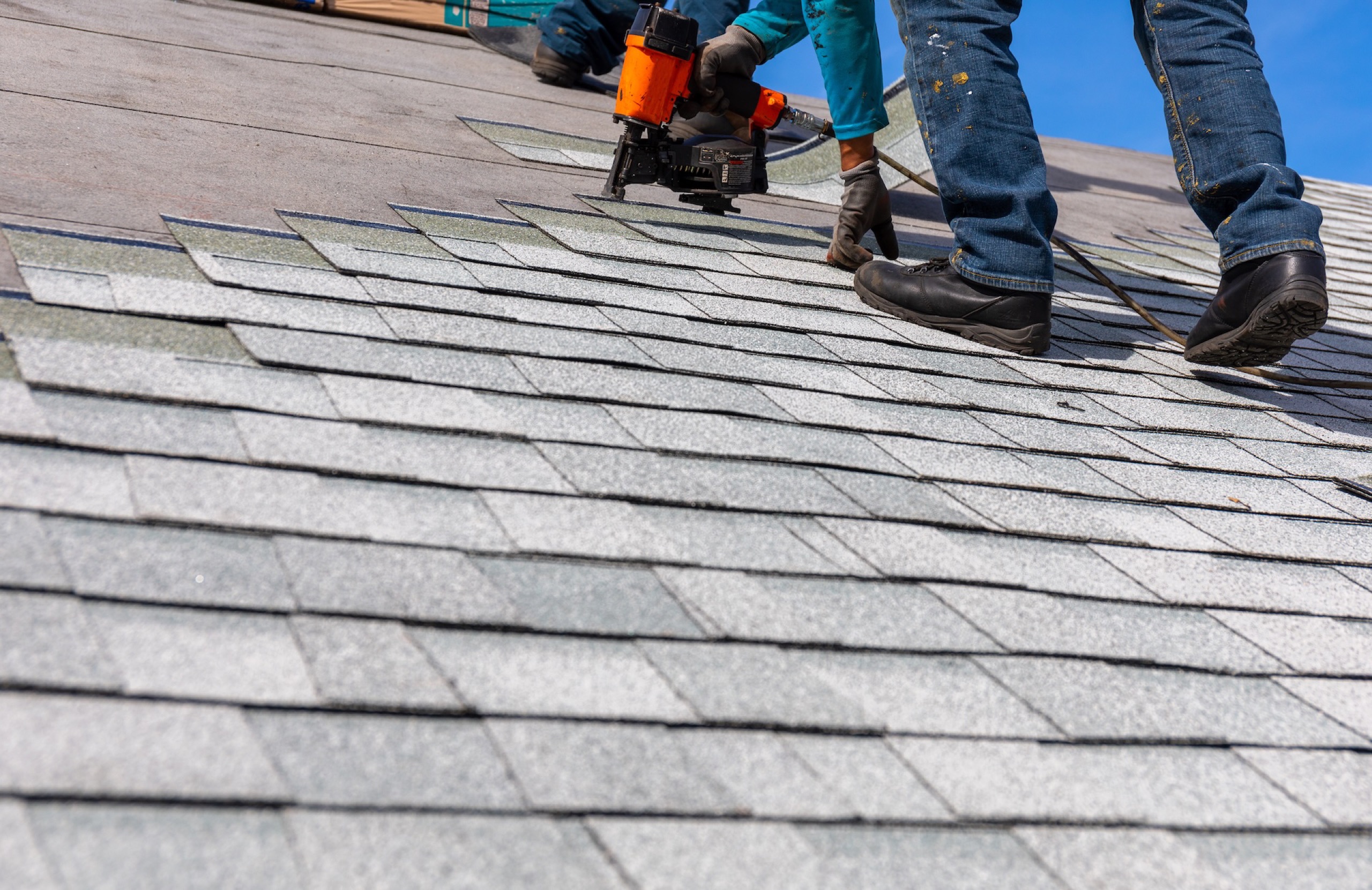 Roofing crew installing architectural shingles on a residential roof